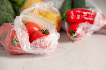 Plastic bags with fresh products on white table, closeup