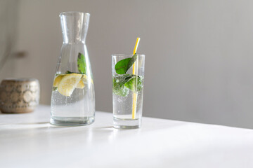 Wasserglas mit Karaffe und Minze steht auf Tisch