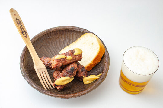 Traditional Romanian grilled minced meat, mici or mititei on a sculpted wood bowl with mustard