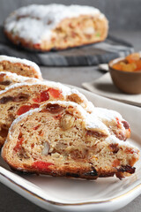 Traditional Christmas Stollen with icing sugar on grey table, closeup