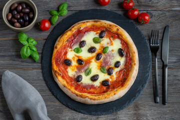 fresh baked pizza with salami, mozzarella cheese and olives on a plate