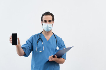 physician in medical mask holding clipboard and smartphone with blank screen isolated on grey.