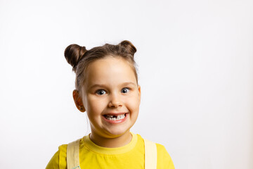 Close-up of shining little girl showing missing front baby tooth and smiling crazily in yellow...