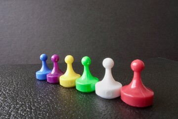 Plastic board game pawns or tokens. Blue, purple, yellow, green, white and red. 