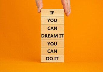 Dream and do it symbol. Wooden blocks with words If you can dream it you can do it. Beautiful orange background, copy space. Businessman hand. Business, motivational dream and do it concept.