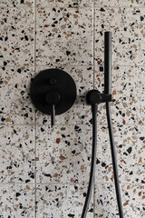 Close-up on black tap in wall with terrazzo tiles