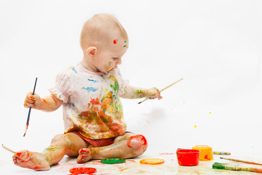 Little girl soiled by multi-colored paints on a white background