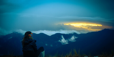 young woman watching the sunrise in the mountains