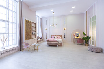 Fototapeta na wymiar spacious expensive luxury bright interior of open-plan apartment in pink colors with dressing room, bedroom area and cozy area for guests with soft furniture. fashionable LED lighting and huge windows