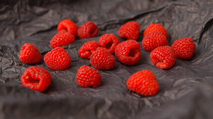 Raspberry fresh fruits photographed on a dark background. Raspberries food photography. Details of this tasty forest fruits.