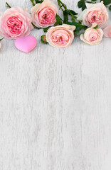 Flowers pink roses with hearts on a white wooden background with space for text. Decoration of Valentine Day