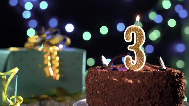 Birthday cake golden candle number 3 three fire from a lighter, blowing out the candles. Copyspace on the left side of the screen.