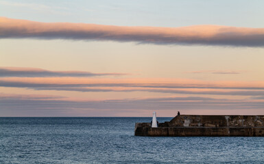 Obraz premium CULLEN, MORAY, SCOTLAND - 23 JANUARY 2022: This is the lines of cloud getting the last rays of the sun in Cullen, Moray, Scotland on Sunday 23 January 2022.