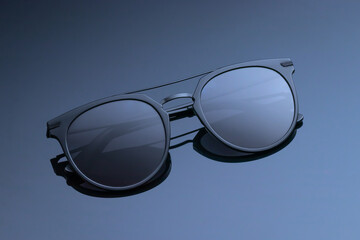 Sunglasses close-up on a dark gray glossy background. Women's black glasses with a gradient....