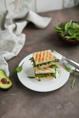 Sandwich with cottage cheese, pea hummus, avocado and young greens of spinach and beets. Nutritious healthy toast for lunch. Photo in light colors.