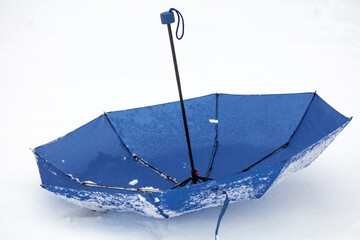 Abandoned blue umbrella on a cold snowy day.
