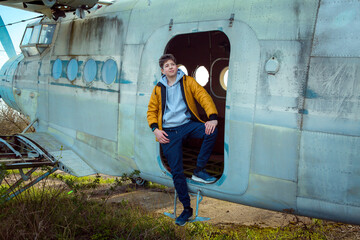 A young man in front of an old abandoned Soviet plane. The guy enjoys learning the old technique