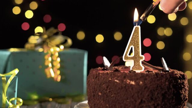 Birthday cake golden candle number 4 four fire from a lighter blowing out the candles. Copyspace on the left side of the screen.
