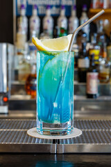 Exotic cold shot glass cocktail with yellow lemon slice, blue curacao, ice cubes