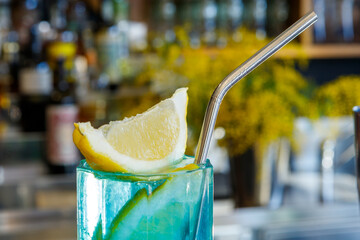 Exotic cold shot glass cocktail with yellow lemon slice, blue curacao, ice cubes