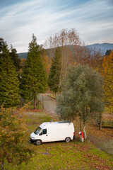 Camper Van charging electricity on a campsite with trees around