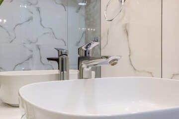 metal water tap with sink and faucet to turn on and regulate cold or hot water in expensive bathroom.