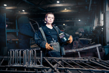 Obraz na płótnie Canvas Worker girl with welding on steel structure in factory, light spark