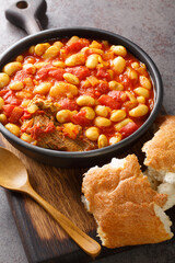 Fototapeta premium Moroccan Stewed White Beans Recipe Loubia with meat closeup in the bowl on the wooden board. Vertical