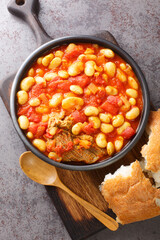 Moroccan Stewed White Beans Recipe Loubia with meat closeup in the bowl on the wooden board. Vertical top view from above