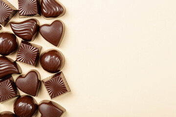 Chocolate pralines assortment on beige background, flat lay, top view with copy space