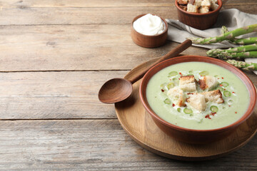 Delicious asparagus soup with croutons served on wooden table, space for text