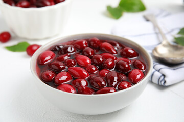 Delicious dogwood jam with berries in bowl on white table, closeup