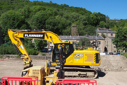 hebden bridge, west yorkshire, united kingdom - 12 june 2021: close up of of a jcb digger vehicle with logo and cat roller truck on a construction site