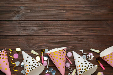 Fototapeta na wymiar Colorful party hats and other festive items on wooden table, flat lay. Space for text