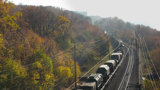 transportation of military equipment by rail.Vehicles and weapons. railway along the mountains covered with forest. Text "flammable" in russian