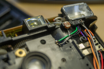 Fototapeta na wymiar Disassembled compact camera. Internal parts of the broken camera being repaired in the workshop. Selective focus