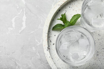 Glasses of soda water with ice and mint on grey table, top view. Space for text