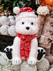 Polar bear toy in a red scarf and hat on a shop window display shelf in christmas