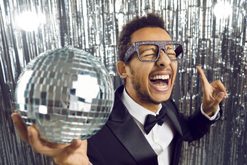 Happy funny guy having crazy fun at party. Confident mixed race Afro Indian man in tux suit, shirt,...