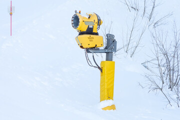 Yellow snow cannon on the slope of the ski slope.