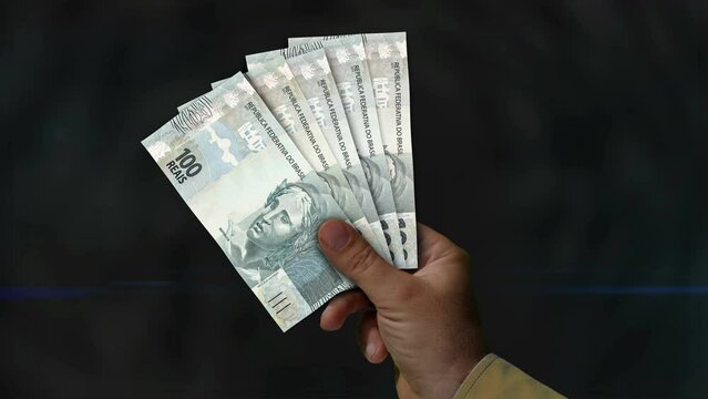Brazil Real, Reai money holding. Fan of banknotes in hand. BRL paper cash. Concept of income, success, business, tax, economy and finance.
