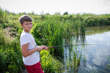 boy fishing in the morning near an overgrown lake in the summer