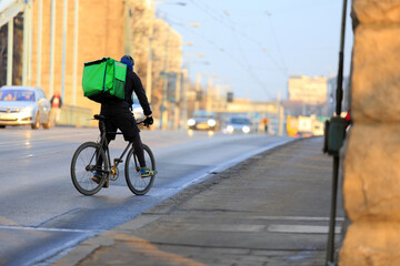 Kurier na rowerze jedzie mostem Grunwaldzkim we Wrocławiu, dostarcza jedzenie. 
