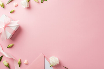 Top view photo of woman's day composition giftbox with bow pink ribbon envelope with card hearts and prairie gentian flowers on isolated pastel pink background with blank space