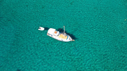 Aerial photo from traditional picturesque fishing boat on emerald clear sea as seen from top in island of Paros, Cyclades, Greece