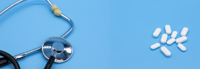 stethoscope and oval-shaped tablets lie on a contrasting background