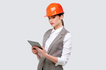 Woman engineer wearing protection helmet and holding tablet computer isolate on grey background