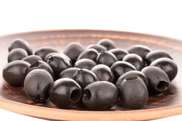 A few pickled black olives on a clay dish, macro, isolated on white.