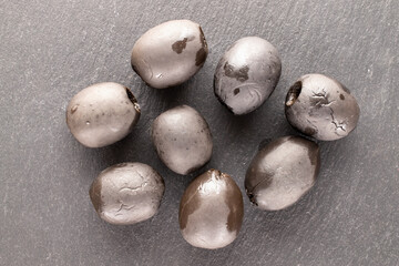 Some pickled black olives on a slate stone, macro, top view.
