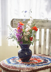 Still life with fresh wild flowers in vase on vintage chair